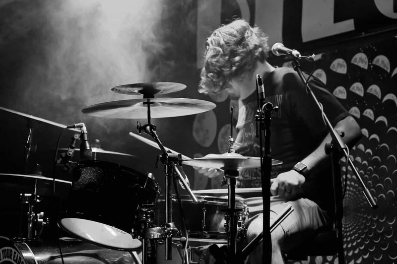Black and white photo of the drummer playing in stage haze