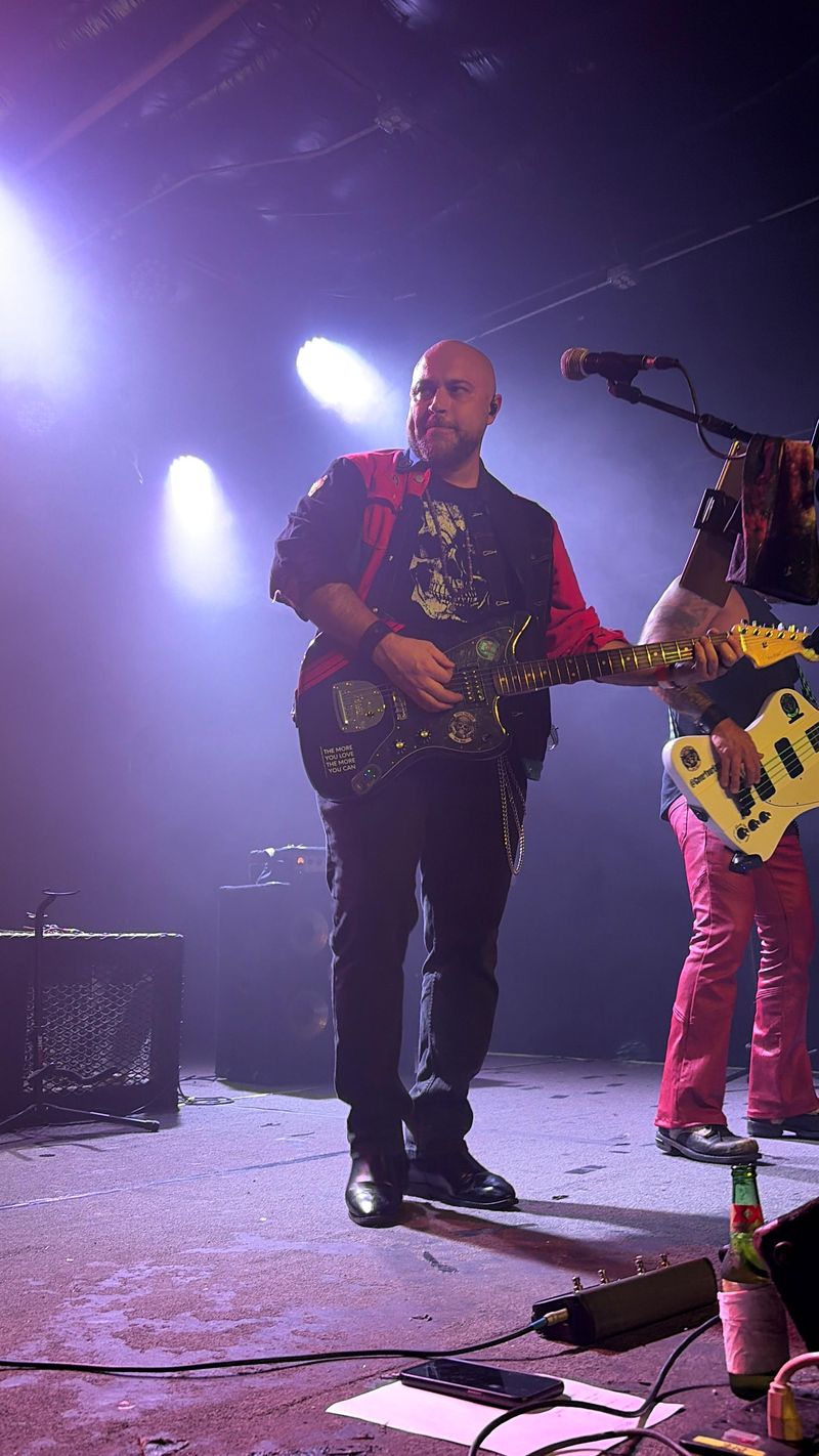 Carlos on stage with his guitar under purple spotlights