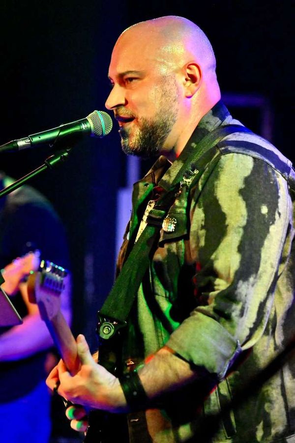 Close-up of Carlos singing into the mic under green light