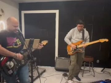 Two guitarists rehearsing in a practice room